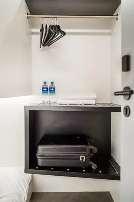 a shelf with two bottles of water and a suitcase at THIS HO(S)TEL in Amsterdam