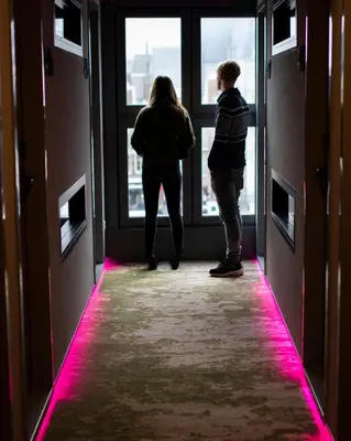 two people standing in a hallway looking out the window at THIS HO(S)TEL in Amsterdam
