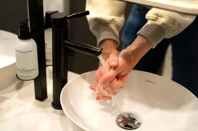 a person is washing their hands in a sink at THIS HO(S)TEL in Amsterdam