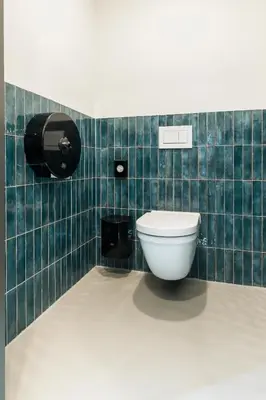 a bathroom with a toilet in a green tiled wall at THIS HO(S)TEL in Amsterdam