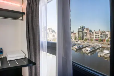 a room with a window with a view of a harbor at THIS HO(S)TEL in Amsterdam