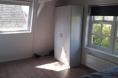a bedroom with a bed and two windows at bij San & Ka in Hauwert