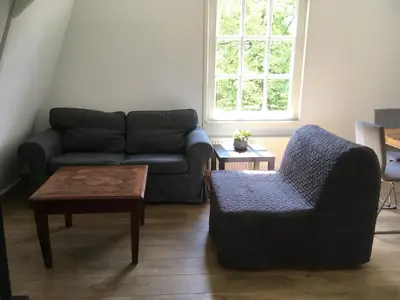 a living room with a couch and a chair at bij San & Ka in Hauwert