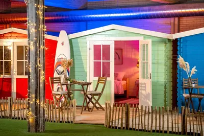 a beach shack with a table and a surfboard at Outside Inn in Amsterdam