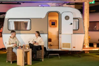 a man and woman sitting in chairs in front of an rv at Outside Inn in Amsterdam