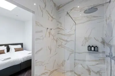 a bathroom with a shower and a bed in a room at Anegang Boutique Appartement in Haarlem