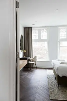 a bedroom with a bed and a desk and window at Anegang Boutique Appartement in Haarlem