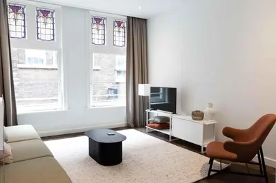 a white living room with a couch and a tv at Anegang Boutique Appartement in Haarlem
