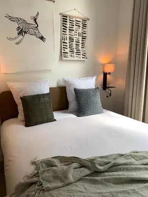 a bedroom with a white bed with a bird picture on the wall at Utrecht City Apartments - Maliesingel in Utrecht