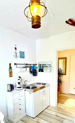 a white kitchen with a sink and a lamp at The Blue Dodo in Zandvoort