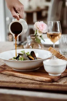 a person pouring wine into a bowl of food at Boutique Hotel - de Stadsherberg Alphen in Alphen aan den Rijn