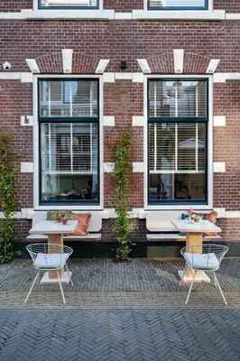two tables and chairs in front of a brick building at Boutique Hotel - de Stadsherberg Alphen in Alphen aan den Rijn