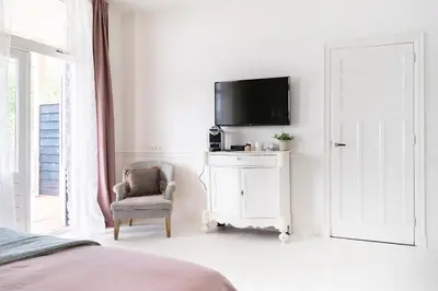 a bedroom with a bed and a tv and a chair at Boutique Hotel - de Stadsherberg Alphen in Alphen aan den Rijn
