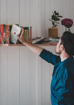 a man is reaching for a book on a shelf at Zwier, de Vrijhaven in Vinkeveen