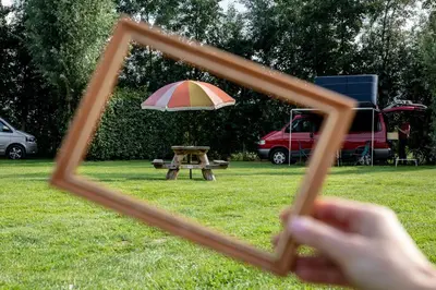 a person taking a picture of a picnic table and an umbrella at Camping de Vliert in Bunnik