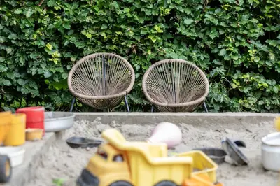 two chairs and a toy truck in front of a hedge at Camping de Vliert in Bunnik