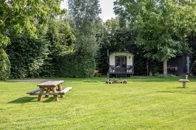 a park with a picnic table and a trailer in the grass at Camping de Vliert in Bunnik