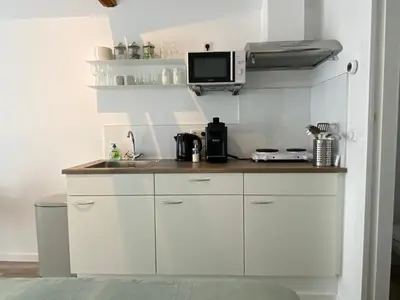 a kitchen with white cabinets and a tv on the wall at Het Krabbehuisje in Zandvoort