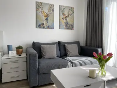 a living room with a couch and paintings on the wall at Het Krabbehuisje in Zandvoort