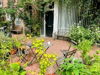a porch with two chairs and a table and flowers at Marijke's guestroom in Amsterdam