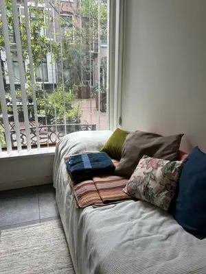 a bed with pillows on it in front of a window at Marijke's guestroom in Amsterdam
