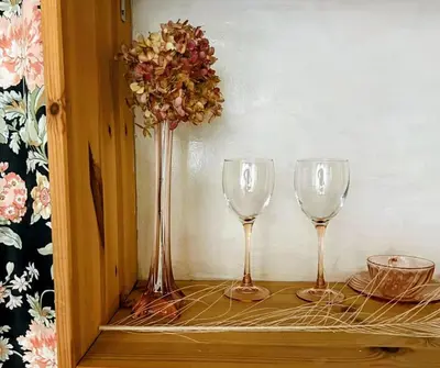 three wine glasses sitting on a shelf with a vase at Marijke's guestroom in Amsterdam
