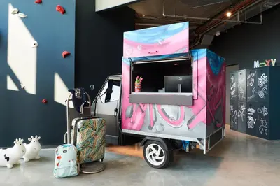 a small food truck parked in a room with luggage at Moxy Amsterdam Schiphol Airport in Hoofddorp
