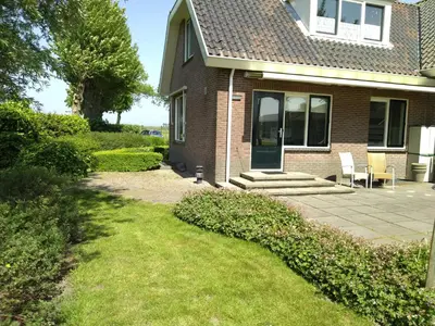 a brick house with a patio and a lawn at Accommodatie op boerderij Buitenlust in Weesp