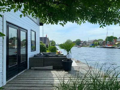 a couch sitting on a deck next to a body of water at Holiday home at the water, fire place, boat and SUP rent, near Amsterdam in Aalsmeer