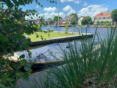 a dock on a body of water with houses at Holiday home at the water, fire place, boat and SUP rent, near Amsterdam in Aalsmeer