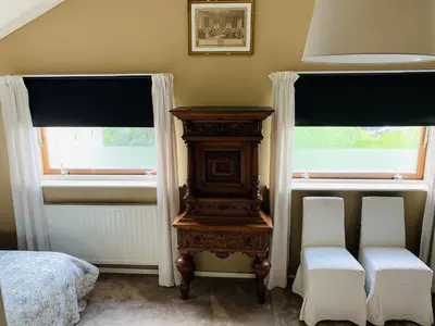 a bedroom with two windows and a bed and a wooden table at Holiday home at the water, fire place, boat and SUP rent, near Amsterdam in Aalsmeer