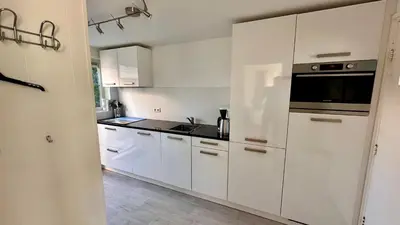 a white kitchen with white cabinets and a sink at Strandhuis Everts in Egmond aan Zee