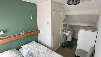 a small room with a bed and a green wall at Strandhuis Everts in Egmond aan Zee