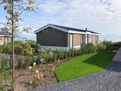 a garden with a building and a yard with grass at Exclusieve vakantievilla ***** Markermeer in Bovenkarspel