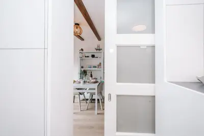 a kitchen with white doors and a dining room with a table at De Jutter - Zandvoort Free Parking in Zandvoort