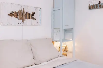 a white bedroom with a bed and a mirror at De Jutter - Zandvoort Free Parking in Zandvoort