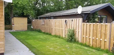 a wooden fence with a house and a yard at Rekerlanden 267 in Warmenhuizen