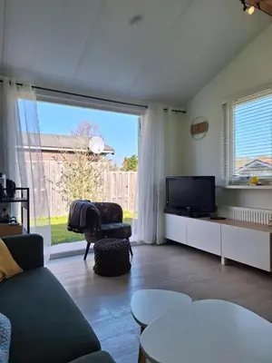 a living room with a large window and a television at Rekerlanden 267 in Warmenhuizen
