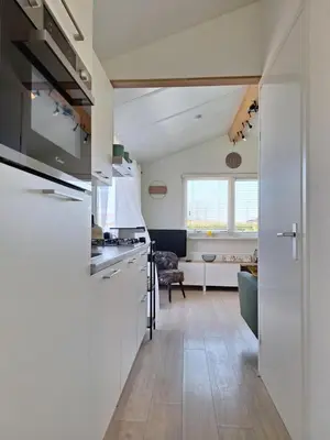 a kitchen with white appliances and a living room at Rekerlanden 267 in Warmenhuizen