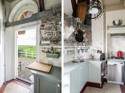 a kitchen with white cabinets and a stone wall at Mondriaanmolen, a real Windmill close to Amsterdam in Abcoude