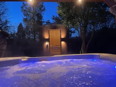 a jacuzzi tub at night with a wooden door at Wellness Bungalow Bolder 5p Amsterdam and the beach in Opmeer