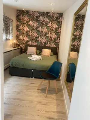 a bedroom with a bed and a chair and a mirror at Mara's Place in Zandvoort