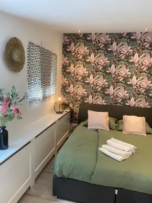 a bedroom with a green bed and a floral wall at Mara's Place in Zandvoort