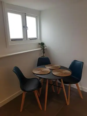 a table and chairs in a room with two windows at Mara's Place in Zandvoort
