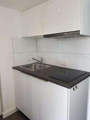 a kitchen with white cabinets and a sink at Mara's Place in Zandvoort