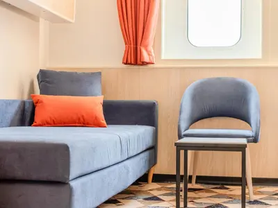 a blue couch with an orange pillow and a chair at DFDS Ferry - Amsterdam to Newcastle in IJmuiden