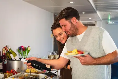 a man holding a wine bottle and a woman holding a plate of food at DFDS Ferry - Amsterdam to Newcastle in IJmuiden