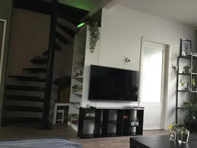 a living room with a flat screen tv and a staircase at Beemster Experience in Middenbeemster