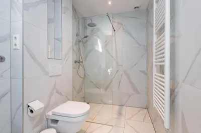 a white bathroom with a shower and a toilet at Charming Apartments in Alkmaar