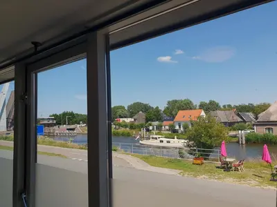 a window with a view of a river and a boat at Hof van Schoorl in Schoorldam